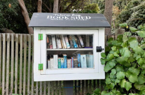 Small wooden book shed attached to a fence