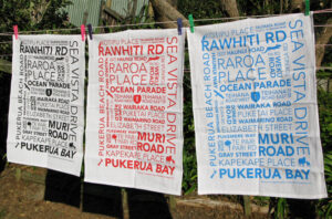 Three tea towels hanging on a clothes line. Each with a typographic design.