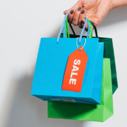 A hand holding colourful paper shopping bags on a white background