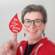 Smiling woman with a sticker on her finger that reads 'be nice to me I gave blood today'